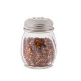 A clear Swirl Shaker from TableCraft Products, filled with crushed red pepper flakes and topped with a metal lid featuring several holes for sprinkling, is shown against a plain white background.