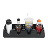 A black plastic cup holder organizer with four compartments holds a white travel mug, a glass bottle with dark liquid, a large disposable cup with lid and straw, and an orange sports drink bottle. The organizer sits on a plain white background.