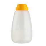 A clear, BPA free plastic squeeze bottle with a bright yellow flip-top cap stands upright against a white background. This 48 oz dispenser features a simple, rounded shape, slight side ridges for grip, and is dishwasher safe for easy cleaning.