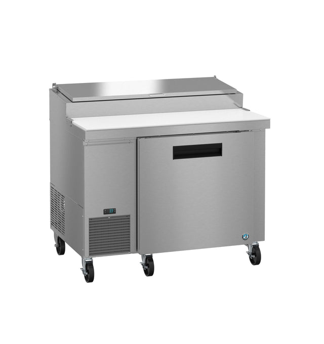 A commercial Hoshizaki stainless steel pizza prep table with a refrigerated base, cutting board surface, and lid. Features one door, a digital temperature display, and four black caster wheels for mobility; ideal for restaurant kitchens.