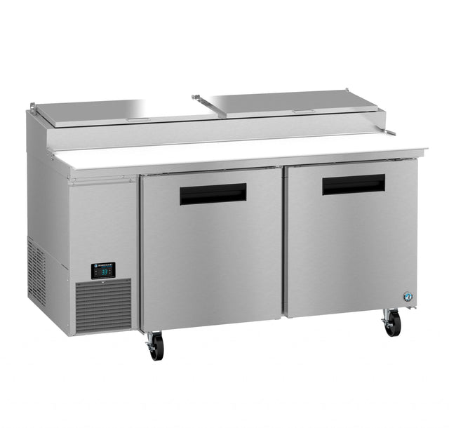 The Hoshizaki Steelheart Series pizza prep table features a commercial stainless steel build, two doors, a lower refrigeration unit, four wheels, and a raised back section with two lidded compartments and a white cutting board surface.
