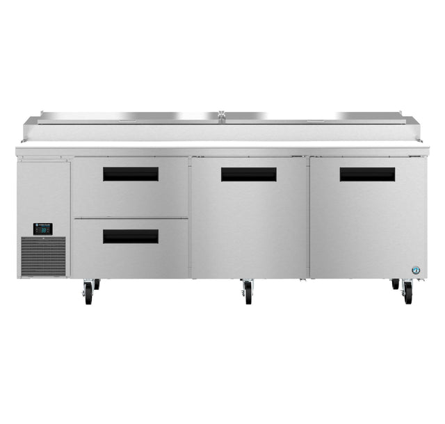 A large stainless steel pizza prep table features two refrigerated drawers on the left, two swing doors on the right, a digital control panel, bottom-left ventilation, four caster wheels, and an integrated prep station on top.