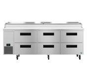 A large commercial stainless steel pizza prep table with six black-handled refrigerated drawers, a digital control panel on the left, and four caster wheels. The top features a covered compartment for food storage or ingredients.