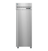 A tall, silver, commercial pass-thru refrigerator stands on small caster wheels. The front features a vertical handle on the left, vents and a digital temperature display near the top, and a circular logo in the upper left corner.