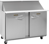 A compact prep table refrigerator by Traulsen, this stainless steel unit features two doors, a white countertop with a raised back, closed lid, and four black caster wheels. Each door handle displays the Traulsen brand label.