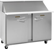 A stainless steel Traulsen compact prep table refrigerator with two doors, white countertop, raised back edge, and a closed angled lid. Features handles, wheels for mobility, and “Traulsen” brand labels on both doors. Perfect as a reach-in refrigerator.