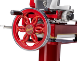 Close-up of a vintage red Berkel Fly Wheel Slicer, highlighting the ornate handwheel with floral spokes and yellow lettering, chrome edge, and part of the slicing mechanism with a chromium-plated carbon steel knife. Polished metal details complete its glossy red look.
