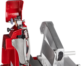 A close-up view of a red and silver Berkel Fly Wheel Slicer features its chromium-plated carbon steel knife, blade guard, and adjustable thickness knob. The upper protective cover is open, revealing the clean inner mechanism against a black background.