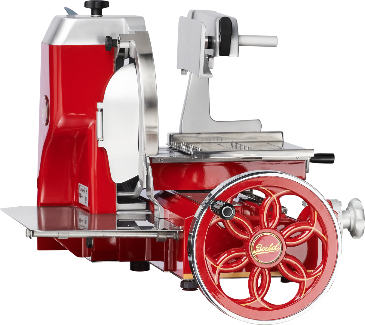 A red and silver vintage-style Berkel Fly Wheel Slicer features a chromium-plated carbon steel knife, stainless steel blade guard, tray, and gears, with a large hand-crank wheel, viewed from the side on a white background.