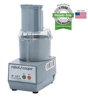 A silver Robot Coupe R101P Combination Food Processor with a clear bowl and lid sits on a white background. A green and gray badge advertises a 1-year hassle-free warranty, while a small American flag appears beside it.