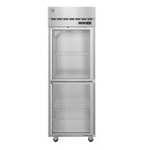 A tall Steelheart Series Refrigerator with a glass door is divided into two sections, each with a white wire shelf. This stainless steel reach-in refrigerator stands empty on four wheels, with the digital control panel at the top right.