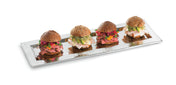 A rectangular stainless steel tray holds four mini sandwiches with seeded buns, filled with deli meat, cheese, leafy greens, and vegetables, arranged neatly in a row on a white background.