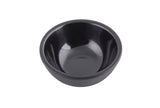 A small, empty black ramekin with smooth, glossy sides and a ribbed texture sits centered on a white background. The bowl features a simple, modern design and appears to be made of melamine or ceramic.