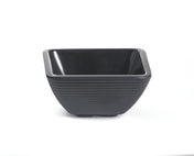 A square-shaped black melamine bowl with gently flared sides and horizontal textured ridges on the exterior, resting on a white background. The bowl has a glossy interior, matte finish outside, and is dishwasher safe.