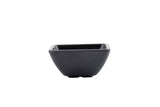 A small, black, square-shaped melamine bowl with gently ridged sides and a matte finish is centered on a white background. The minimalist ramekin design is both modern and dishwasher safe.
