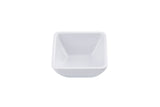 A small, empty, white, square ceramic ramekin with slightly rounded edges sits on a white background, viewed from above at a slight angle.