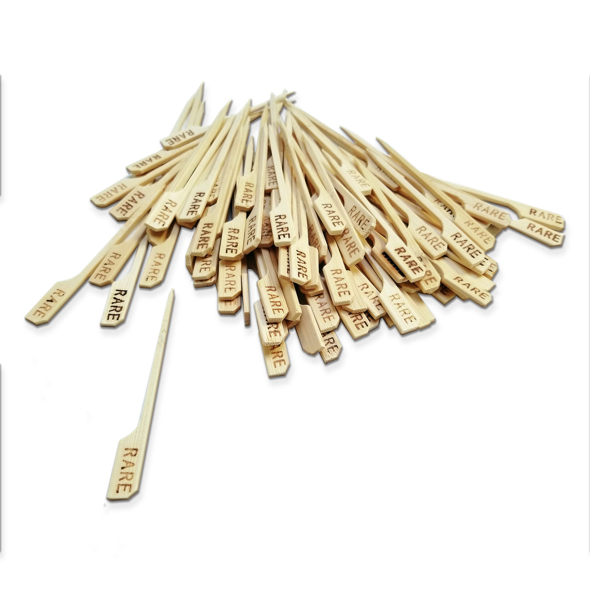 A pile of TableCraft bamboo Meat Marker Picks, each with a flat end engraved with "RARE" in black lettering. One pick is separated from the group in the foreground, all set against a white background.
