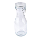 A clear, empty glass carafe with a rounded body and narrow neck, topped with a re-sealable hinged lid secured by a metal clasp. The bottle is photographed against a plain white background.