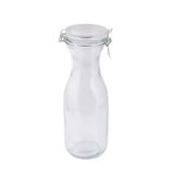 A clear, empty 34 oz glass carafe with a wide base and narrow neck stands upright. It features a round, airtight lid secured by a metal clasp, set against a plain white background.