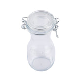 A clear, empty glass jar with a round body, wide neck, and a re-sealable glass lid secured by a metal wire clasp. The jar is pictured against a white background, highlighting its transparency and simple, functional design.
