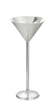 A tall, elegant martini glass from the Remington Collection, crafted in shiny hammered stainless steel with a wide conical bowl, long thin stem, and round base—all with a reflective silver finish—set against a white background.