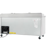 Large rectangular Empura Refrigeration commercial freezer shown from the back, with a vented compressor, stainless steel exterior, four wheels, two handles on top, and a power cord extending from the compressor housing. Warning labels are visible.