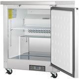 A stainless steel Empura E-KUC27F undercounter reach-in freezer stands on four caster wheels with its door open, revealing two wire shelves inside. The interior is clean and spacious, with a digital control panel displaying 0.0 at the bottom front.