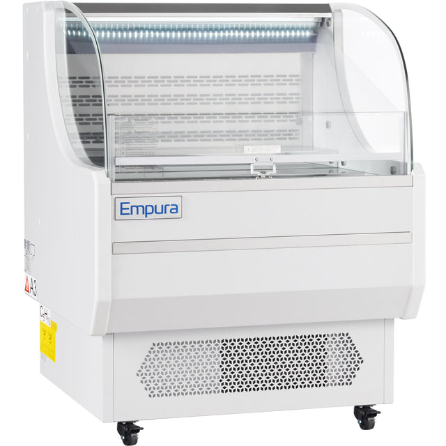 The Empura Refrigeration 7.5 cu. ft. display case features a curved glass front, white body, vented base, and caster wheels for mobility. This open air merchandiser is empty and showcases the Empura brand name on the front panel indoors.