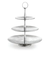 A three-tiered silver serving stand from the Remington Collection Serving Set features round, textured plates that decrease in size upward. The central column has a handle for easy carrying, and the background is plain white.