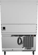 The image shows the back of a large, silver, wheeled appliance—likely a commercial freezer or refrigerator with a refrigerated base. Visible are ventilation grilles, a coiled power cord, drain hose, and panel with screws. The appliance stands on two black wheels.