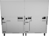 The image shows the back view of a large, metallic, rectangular restaurant range with a split down the middle, mounted on four caster wheels. Ventilation holes, panels, and ports suggest it's modular or integrates features like a charbroiler or gas griddle.