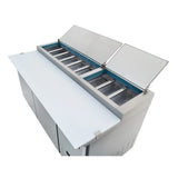 A commercial Empura Refrigeration pizza prep table features stainless steel construction, two open hinged lids revealing empty ingredient trays, a large white cutting board in front, and storage cabinets below.