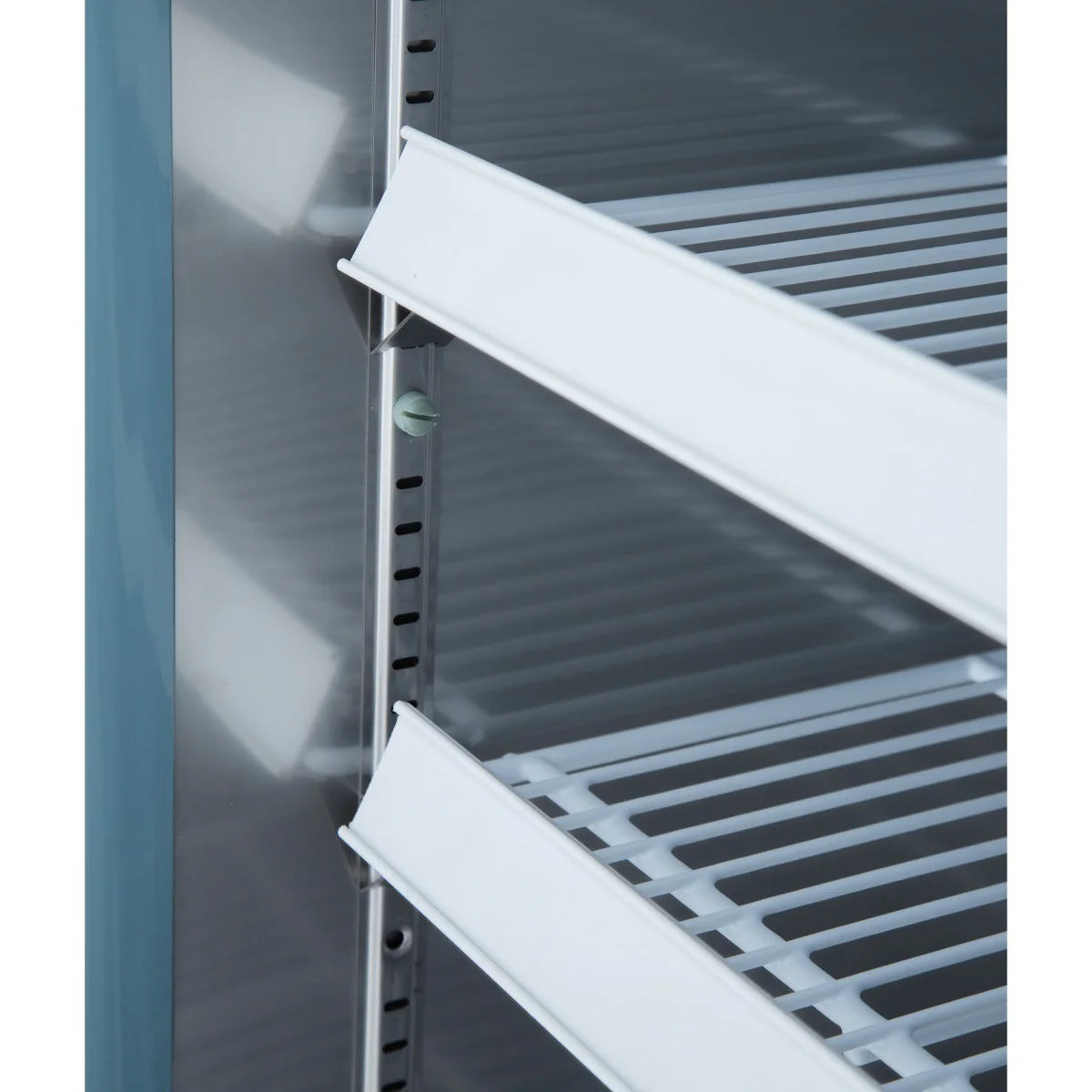 Close-up of the inside of an Empura Refrigeration reach-in refrigerator showing two white metal wire shelves with adjustable height slots. The shelves are slanted downward, and the clean, metallic interior offers a professional finish.