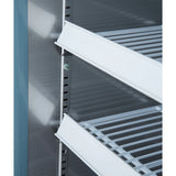 Close-up of the inside of an Empura Refrigeration reach-in refrigerator showing two white metal wire shelves with adjustable height slots. The shelves are slanted downward, and the clean, metallic interior offers a professional finish.
