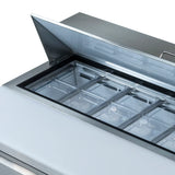 A close-up of an Empura Refrigeration Salad Prep Table with the lid open, revealing transparent rectangular containers arranged in rows inside for storing ingredients. The stainless steel surface and handle on the lid highlight its commercial design.