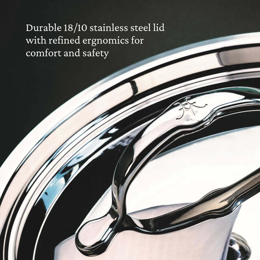 Close-up of a shiny stainless steel lid with a curved handle and engraved logo, reflecting light to highlight its polished finish. Featured is the Hestan Probond Saucepan 3.0qt covered saucepan, offering refined ergonomics for comfort and safety.