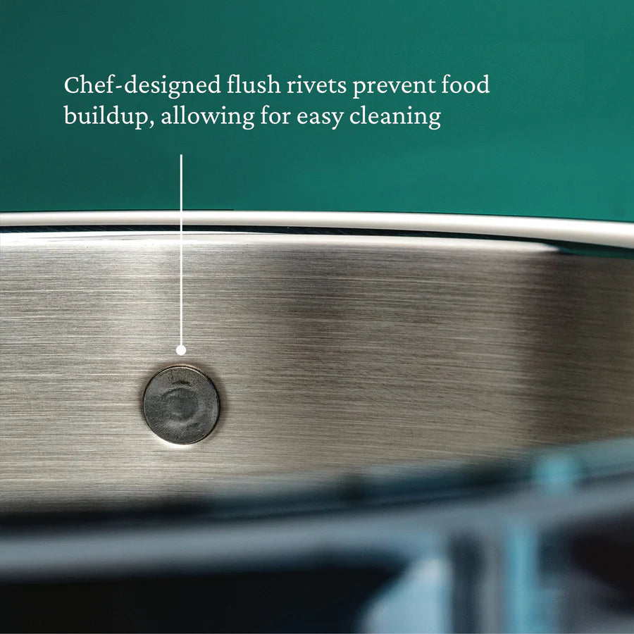 Close-up of a Hestan Probond Saucepan with a chef-designed flush rivet on the inner wall. A label highlights that flush rivets prevent food buildup and allow easy cleaning. The background features a solid teal color.