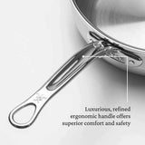A close-up of a polished stainless steel Hestan Probond Essential Pan handle with an ergonomic, curved design. An arrow points to the handle with text: “Luxurious, refined ergonomic handle offers superior comfort and safety.” The pan’s shiny surface is visible.