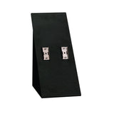A black, angled stand with two silver metal clips attached to its front, set against a white background. This minimalist plastic stand is ideal for showcasing small items such as jewelry or accessories.