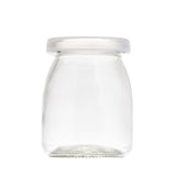 A clear, empty glass jar with a wide base, rounded shoulders, and a narrow neck. This single-serve jar features a smooth, translucent plastic lid. The background is completely white, making the jar’s details clearly visible.