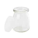 A small, clear glass jar with a wide mouth sits on a white background. The single-serve jar’s white plastic lid is removed and rests against its side. The jar is empty, clean, slightly rounded, and dishwasher safe for easy cleaning.