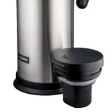 A stainless steel thermos with vacuum insulation and a detached black plastic lid sits upright. The lid rests in front, showing its threading and pouring mechanism. A small Zojirushi logo appears near the base of this sleek beverage server.