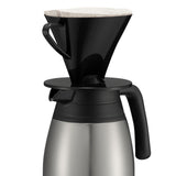 A black plastic coffee dripper with a paper filter sits atop a stainless steel beverage server with a black handle and lid, ready for pour-over coffee brewing. The setup boasts excellent heat retention and looks clean and minimal against a white background.