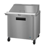A Hoshizaki Steelheart Series Mega Top Refrigerator, this stainless steel commercial prep table features a white cutting board, raised back lid, black recessed handle, four caster wheels, and a lower reach-in refrigerated section for optimal food storage.