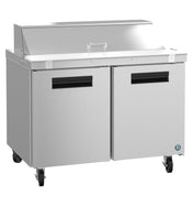 A Hoshizaki Sandwich Top Refrigerator with two doors, a flat worktop, raised covered ingredient section, and black handles. This stainless steel unit has four casters for mobility and a sleek, modern industrial look.