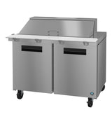 A commercial stainless steel sandwich prep table with a raised mega top refrigerator section, two doors, closed lid, white cutting board, and four caster wheels. The unit features a modern, industrial kitchen design for efficient food prep.