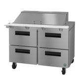 A stainless steel Mega Top Refrigerator prep table featuring four black-handled drawers, a white cutting board surface, a raised covered ingredient section at the back, and caster wheels. This unit offers modern industrial style with practical mobility.