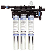 A Scotsman triple water filter assembly with three vertical cartridges, ideal for cubers over 1​ 200 lb, features a pressure gauge on top and black plastic connectors. Each filter is labeled in blue and black text against a white background.