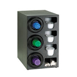 Black organizer with three circular compartments for single-serve coffee pods (blue, green, purple). Beside each pod are cylindrical white creamer containers. At the bottom, two small sections act as straw organizers for white stir sticks.