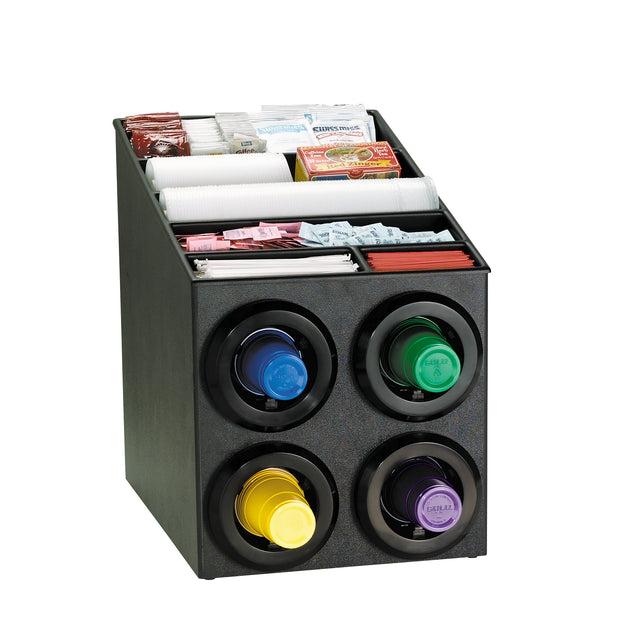 A black countertop cup dispenser cabinet holds four stacks of colored plastic cups in circular dispensers. The top section features compartments for white stirrers, paper cups, napkins, and assorted sugar and creamer packets. NSF certified.